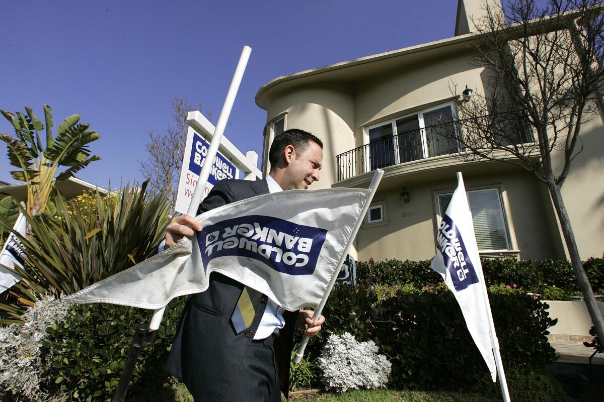 The firm that owns Coldwell Banker and other large real estate brokerages gave a dim prognosis for 2014 home sales May 5. Above, an agent puts signs outside a Santa Monica condo for sale in 2009.