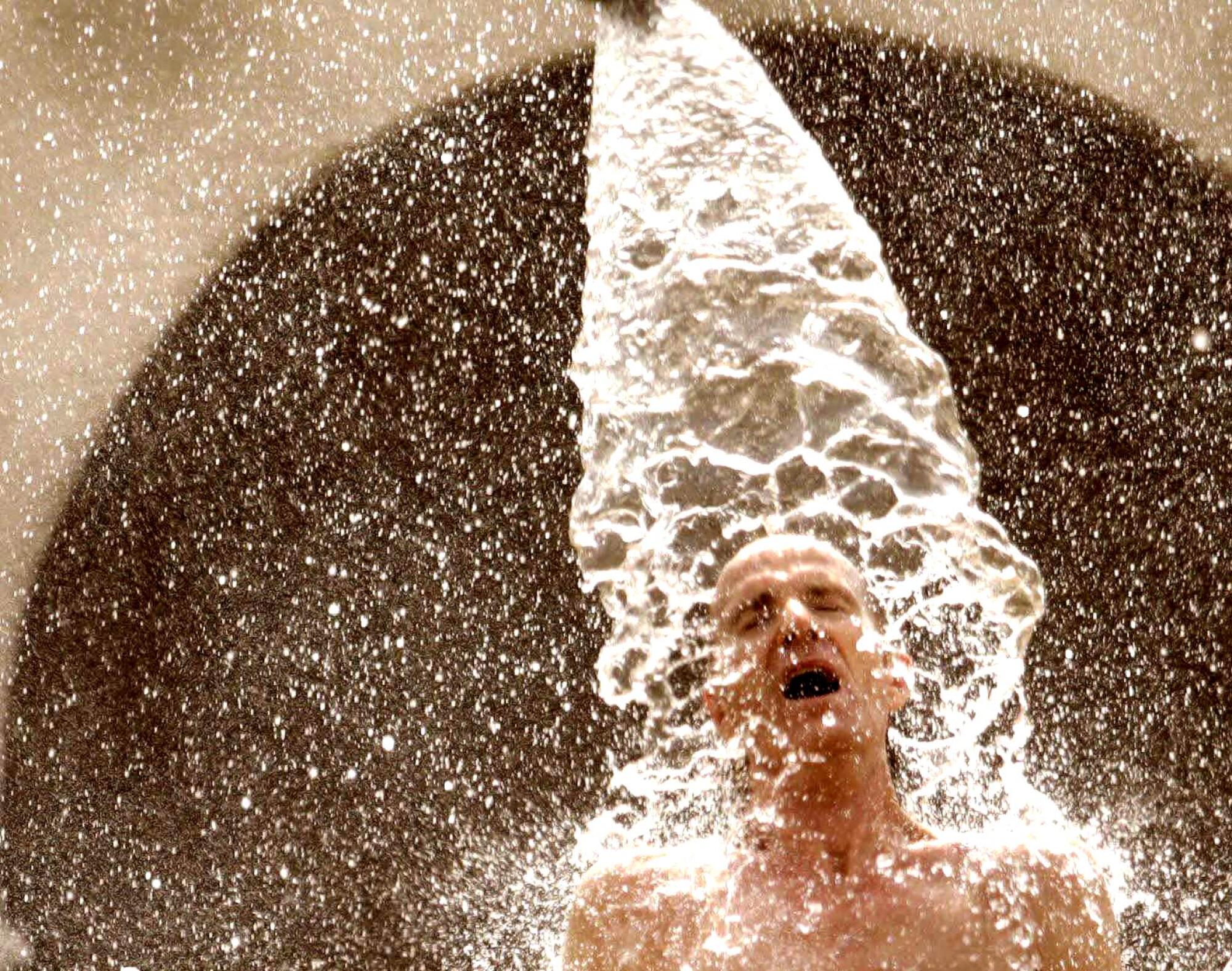 Water splashes down onto a shirtless man