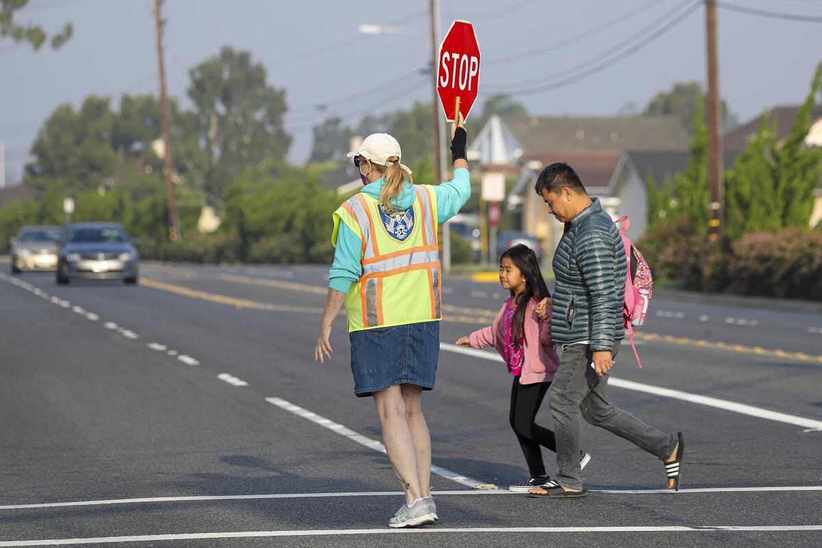 A crossing guard assists families with children near James H. Cox Elementary School in Fountain Valley.