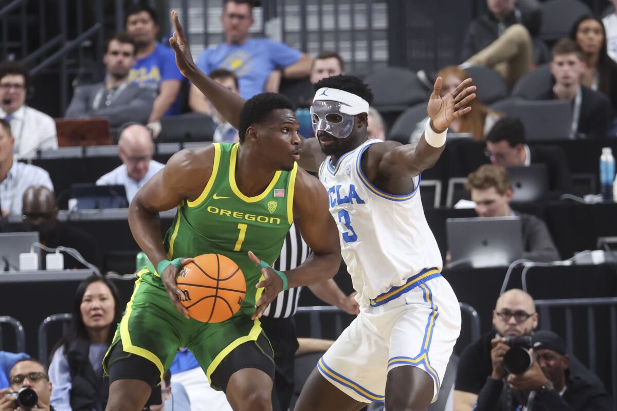 Oregon center N'Faly Dante looks to pass the ball as UCLA forward Adem Bona defends.