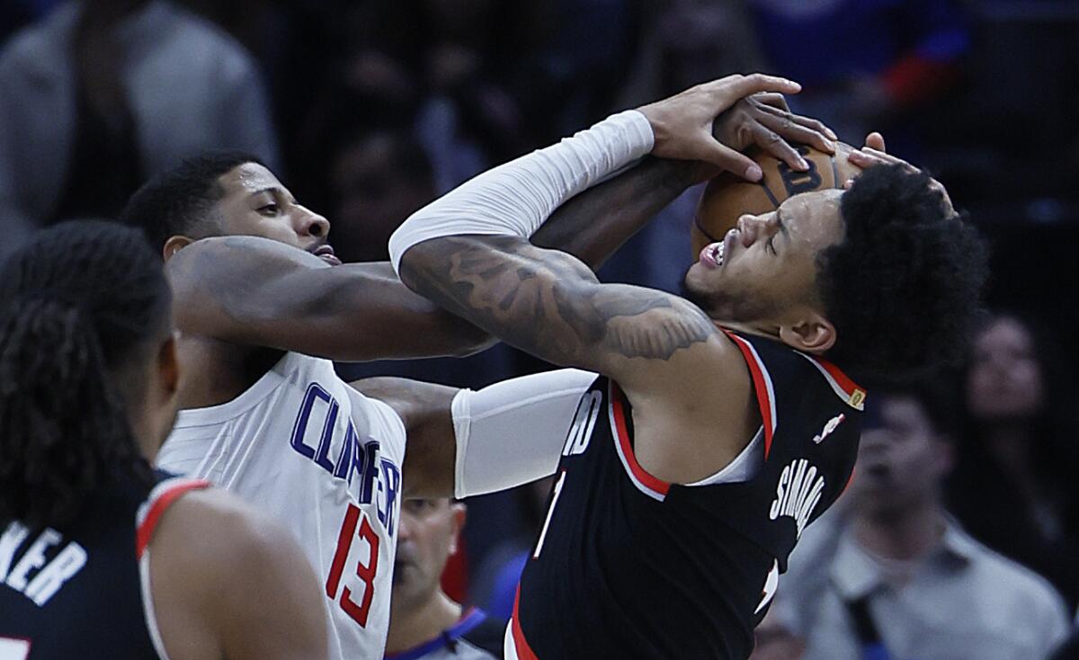 Clippers forward Paul George, left, battles Portland Trail Blazers guard Anfernee Simons for the ball.