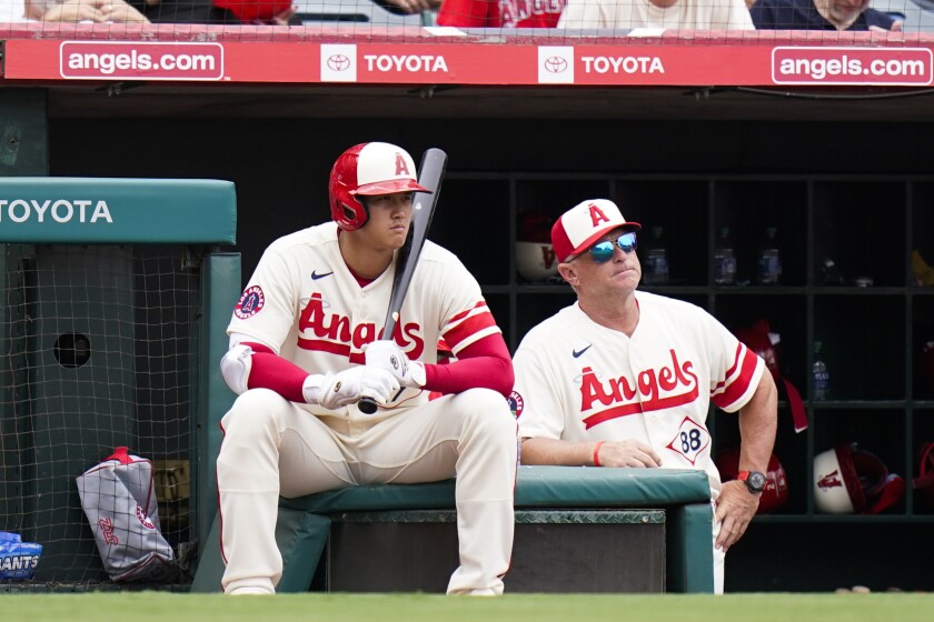 Angels' Shohei Ohtani sits in a box next to interim manager Phil Nevin.