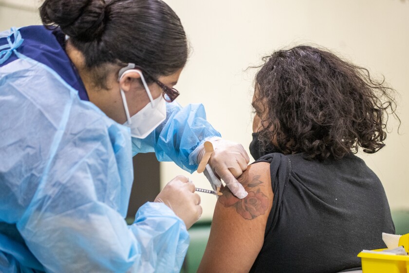 A nurse gives a COVID-19 vaccine to a school worker in Eagle Rock.
