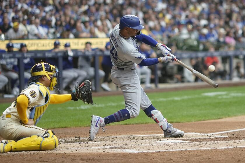 Los Angeles Dodgers' Mookie Betts, right, hits a two-run home run during the third inning of a baseball game against the Milwaukee Brewers, Monday, Aug. 12, 2024, in Milwaukee. (AP Photo/Aaron Gash)