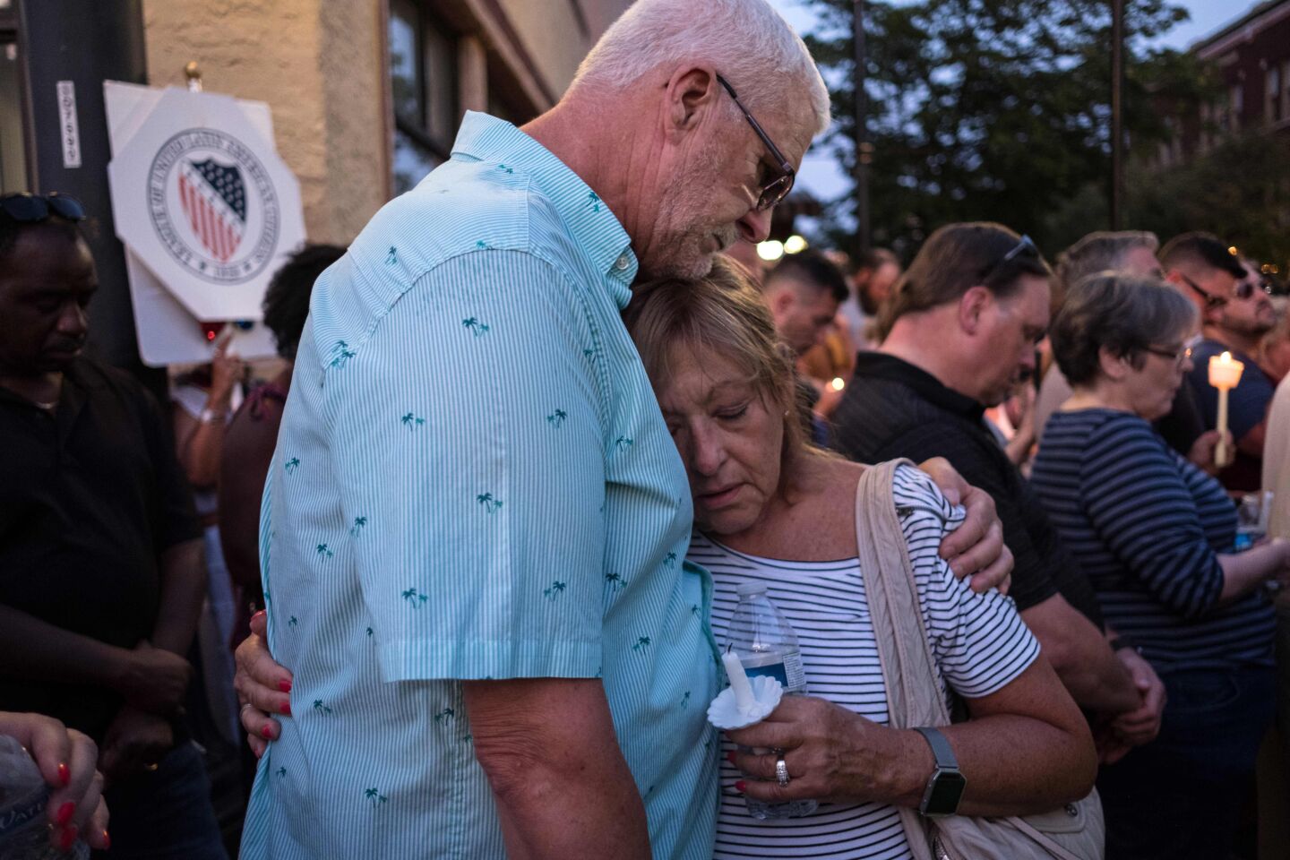 People comfort each other as they take part of a candle lit vigil for shooting victims in Dayton, Ohio.