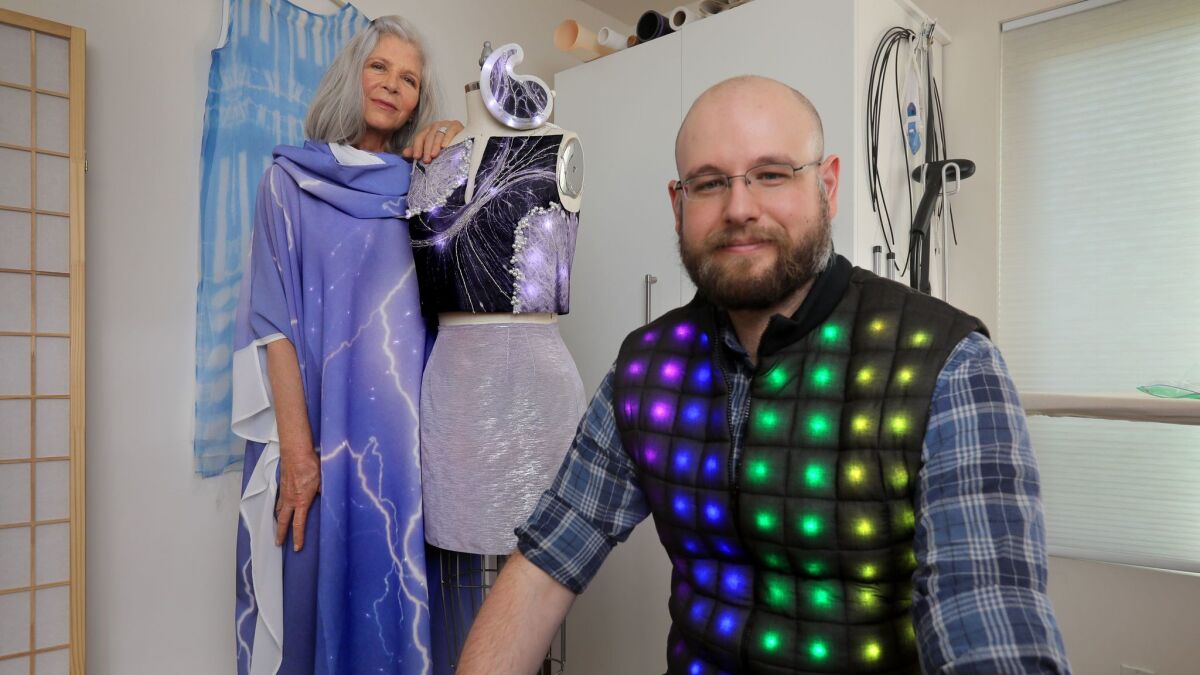 Mother-and-son lighted clothing design team Rachel Merrill and Devon Merrill at her Carmel Valley home and studio. She's wearing their Lightning dress and standing next to their Light Dance project, while he's in their Wearlight vest.