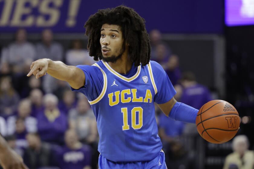 UCLA guard Tyger Campbell directs a play while dribbling against Washington.