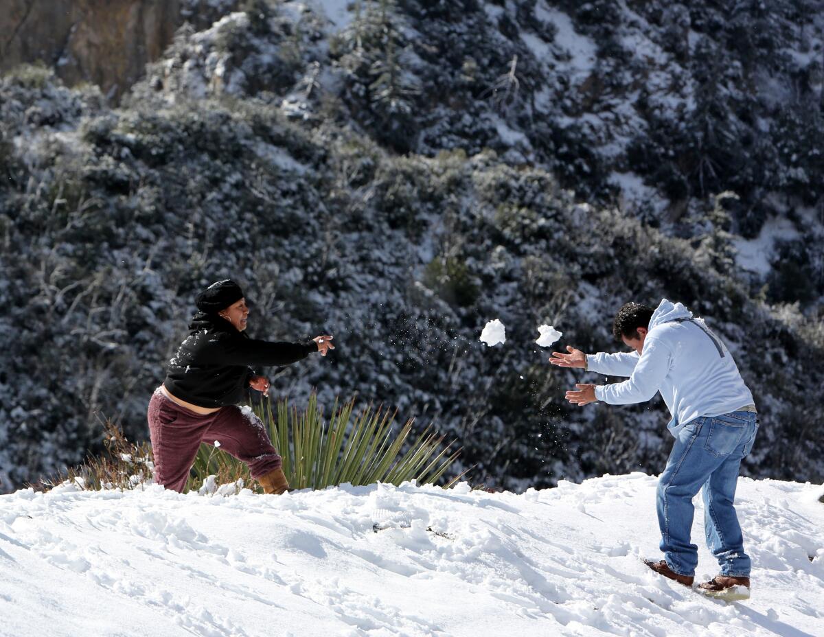 Two men toss snowballs on a roadside