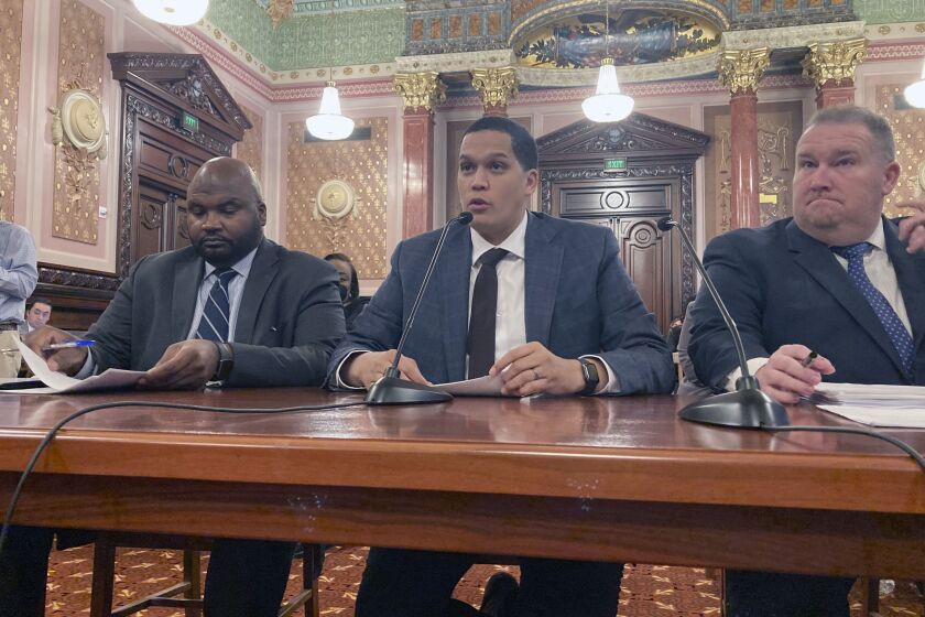 State Sen. Robert Peters, D-Chicago, center, testifies before the Senate Executive Committee on Thursday, Dec. 1, 2022, on his legislation to clarify the SAFE-T Act, a sweeping criminal justice overhaul that notably eliminates cash bail. Accompanying Peters are co-sponsors Sen. Elgie Sims, D-Chicago, left, and Sen. Scott Bennett, D-Champaign. The amendment to the law, which takes effect on Jan. 1, 2023, adds a number of forcible felonies to the list of crimes which qualify a defendant for pretrial detention, but Republicans still have concerns about it. (AP Photo/John O'Connor)