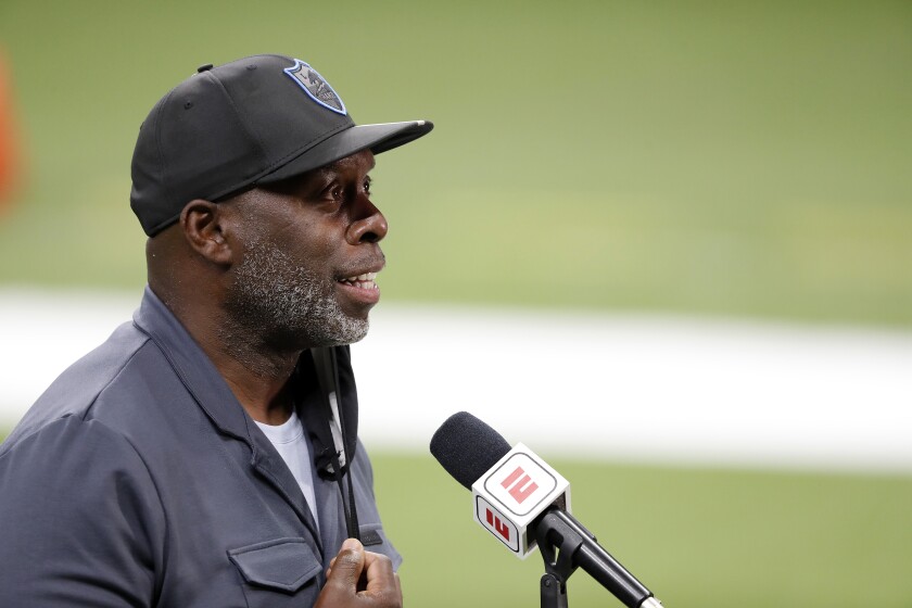 Chargers coach Anthony Lynn speaks into a microphone on the football field.