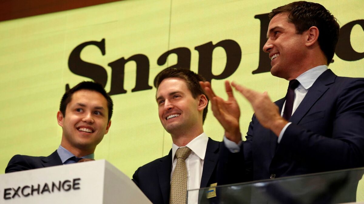 Snap CEO Evan Spiegel, center, and Chief Technology Officer Bobby Murphy, left, ring the bell at the New York Stock Exchange in March.