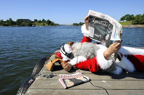 A Finnish Santa Claus listens to music in Helsinki, Finland, as he reads newspapers announcing pop singer Michael Jackson's death.