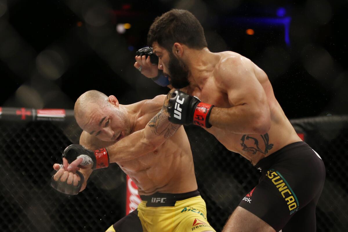 Marlon Moraes, left, and Raphael Assuncao trade punches during their bantamweight fight at UFC 212.