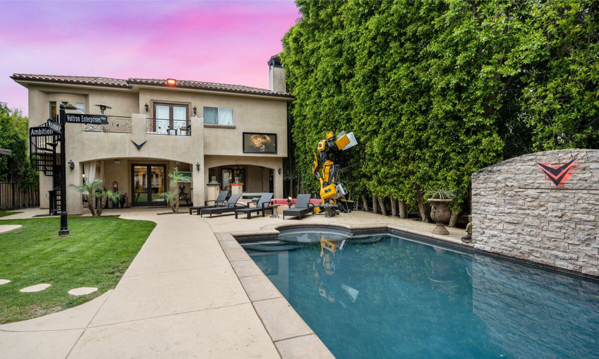 The Mediterranean-style property includes a backyard with a movie screen, pool, street sign and Transformers replica.