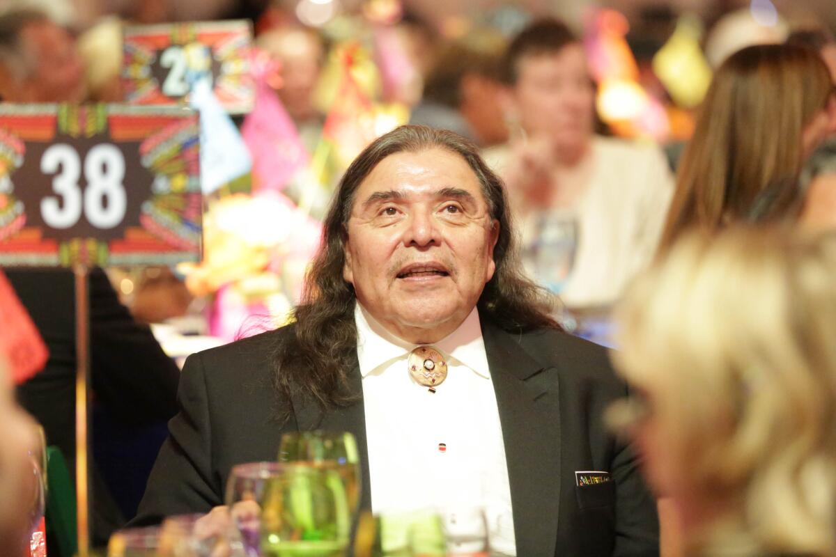 Marshall McKay, his long hair loose around his shoulders, in a formal jacket at a museum event