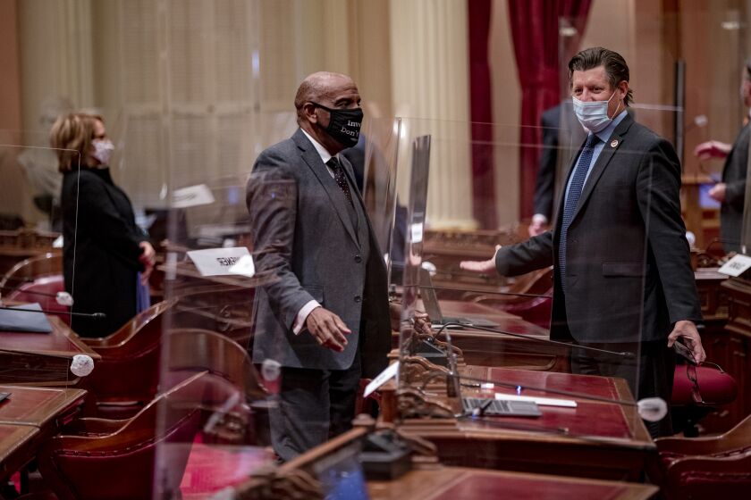 SACRAMENTO, CA -JANUARY 19, 2021: Senators Steven Bradford (D-Gardena), left, and Brian Jones (D-Santee) speak through face masks and plexiglass partitions set up in the Senate chamber because of Covid during a session in the Capitol on January 19, 2021 in Sacramento, California. This is the first time the Senate has met since the Insurrection at the U.S. Capitol on January 6. (Gina Ferazzi / Los Angeles Times)