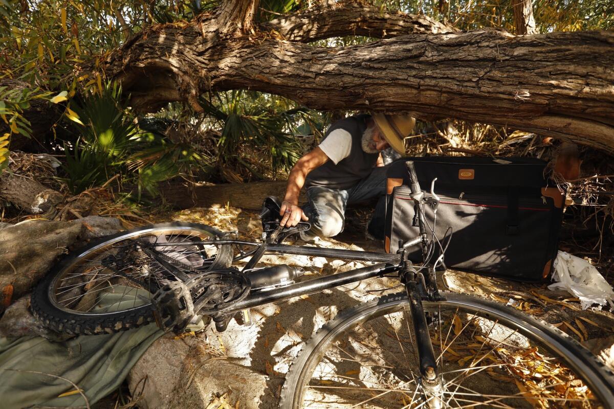 Jesse Herrera, 53, gathers his bike ahead of a storm that could flood his encampment on an island in the middle of the L.A. River near Atwater Village. Herrera, a contract painter who used to live in Atwater, has been living on the island for more than a decade.