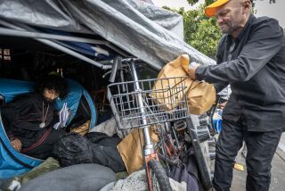 Los Angeles, CA - May 19: Oscar Magana, 22, left, who struggles with mental problems but does not use drugs, sits in his tent as his step father, Johnny Roman, right, 58, who is addicted to meth, bipolar, manic depressive, and ADHD, puts bags of supplies for drug use in their tent encampment near Avalon Boulevard and East Florence Avenue in South Los Angeles Friday, May 19, 2023. The bags of supplies were distributed by a team from Homeless Outreach Program Integrated Care Systems [HOPICS] and includes drug pipes, overdose reversal nasal spray, fentanyl test strips, wipes and educational materials are aimed at preventing infection and disease, and saving them from the fentanyl death crisis. (Allen J. Schaben / Los Angeles Times)