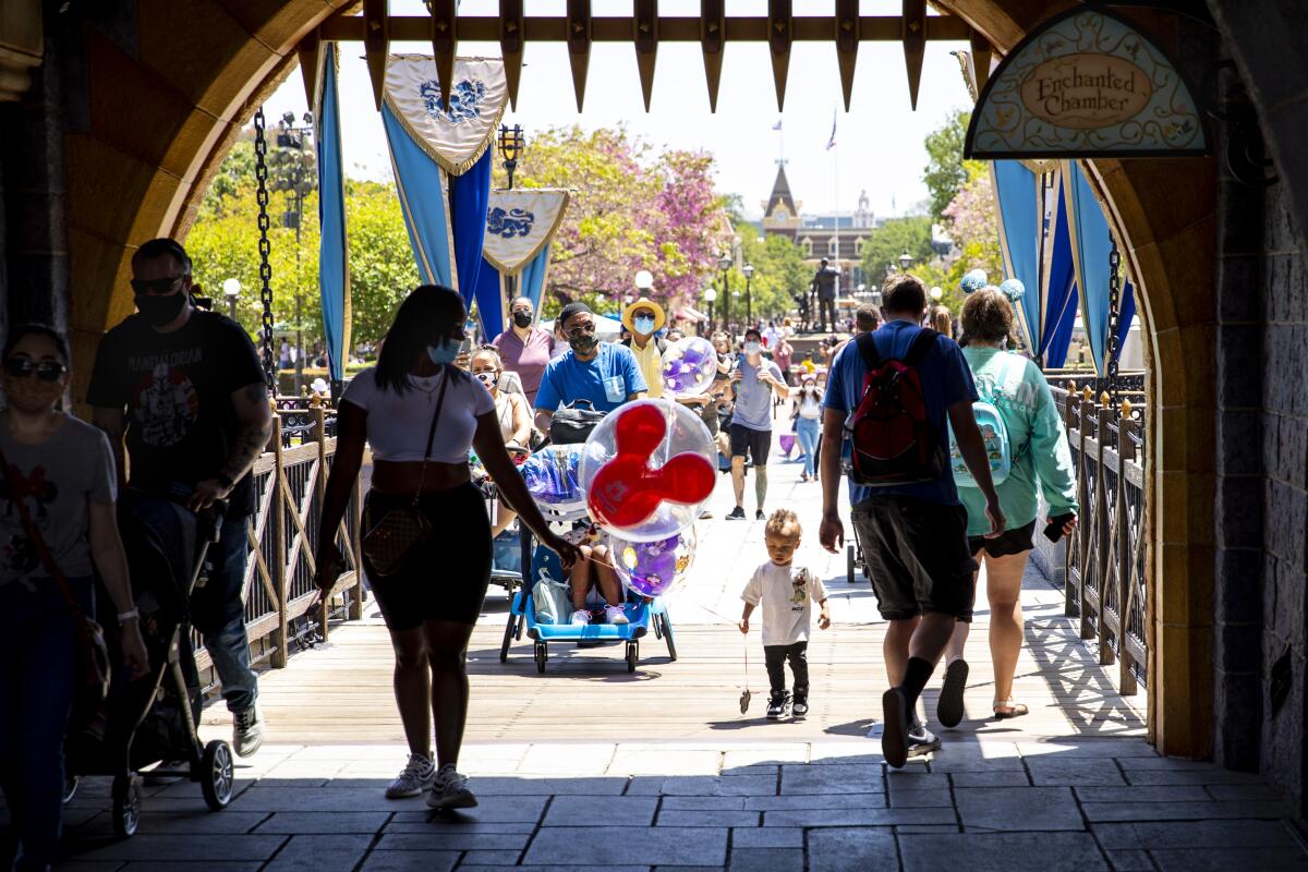 People walk under a gate at Disneyland in Anaheim.

