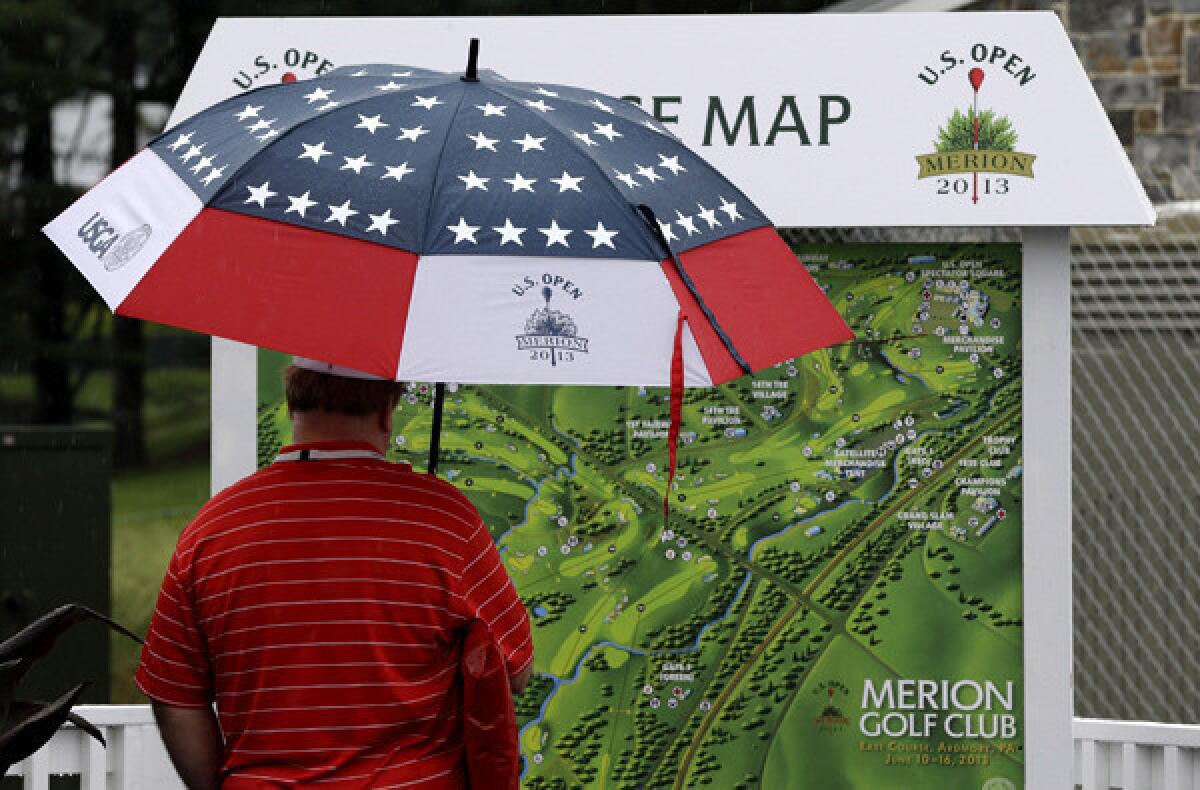 A spectator looks at a Merion Country Club map on Monday, when heavy rains left the course unplayable for several hours.