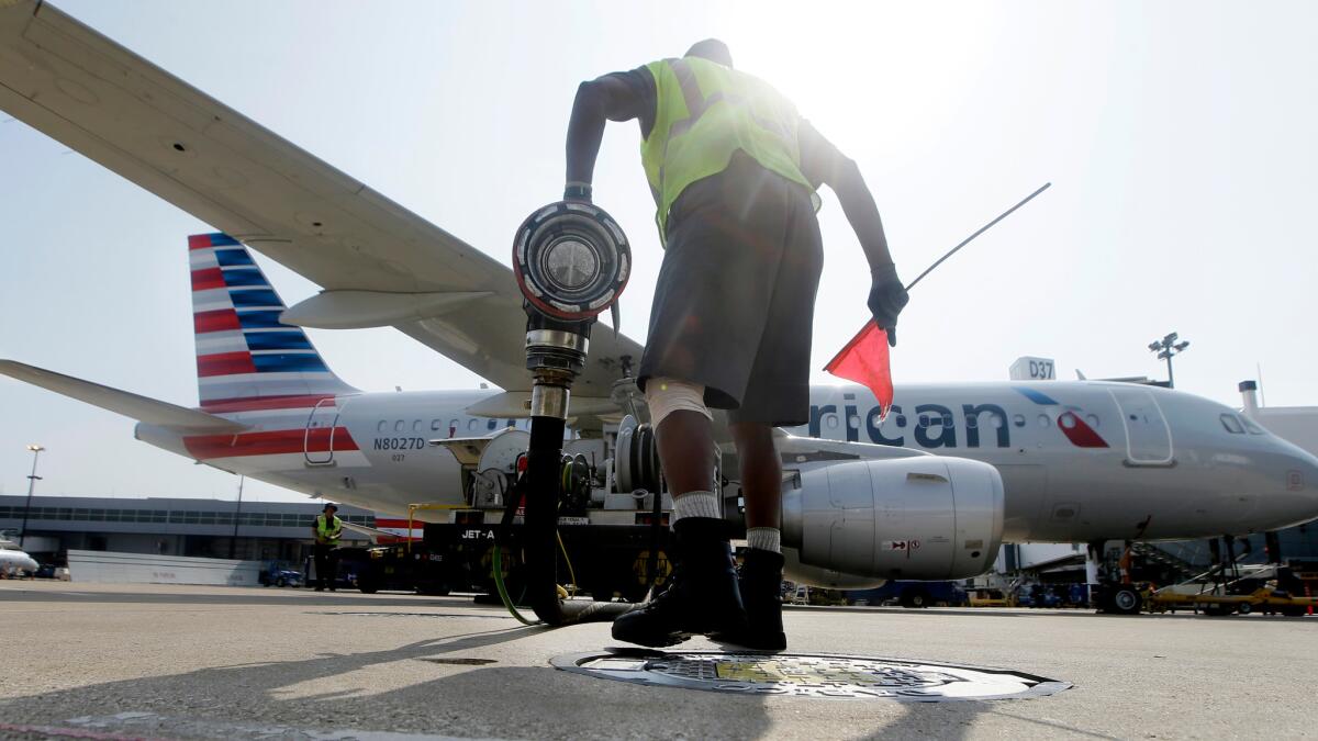 Scott Mills finishes fueling an American Airlines jet at Dallas/Fort Worth International Airport in Grapevine, Texas. Lower fuel costs and increased competition from low-cost carriers are pushing domestic airfares down.