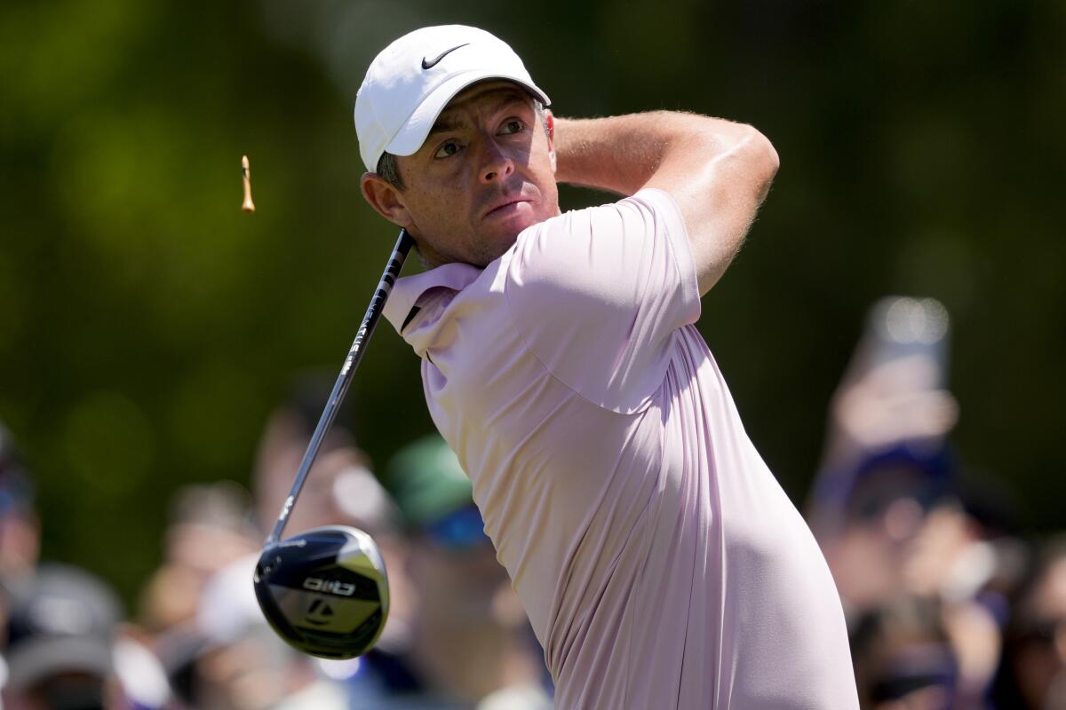 Rory McIlroy swinging a driver while clad in a white ballcap and pink polo shirt
