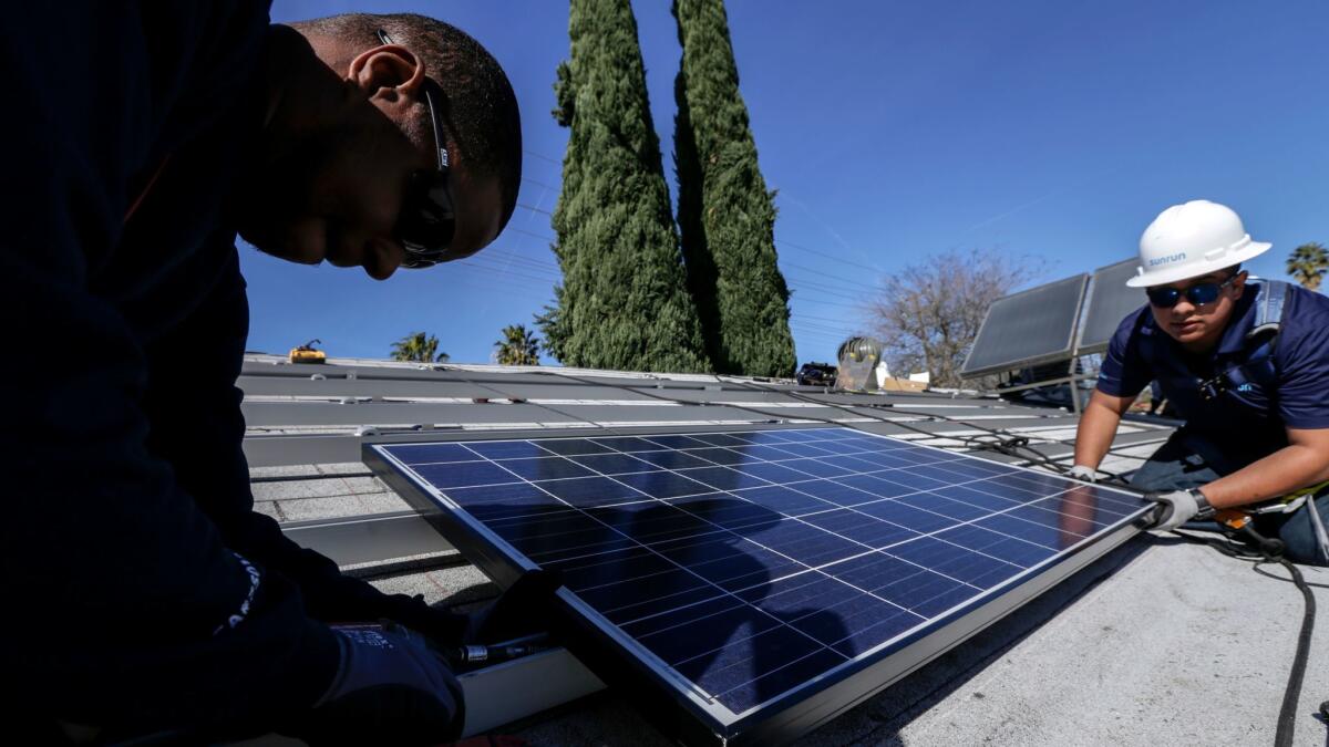 Elgin Clark, left, and Edgar Palma, from Sunrun home solar company, install a solar panel on a home in Van Nuys.