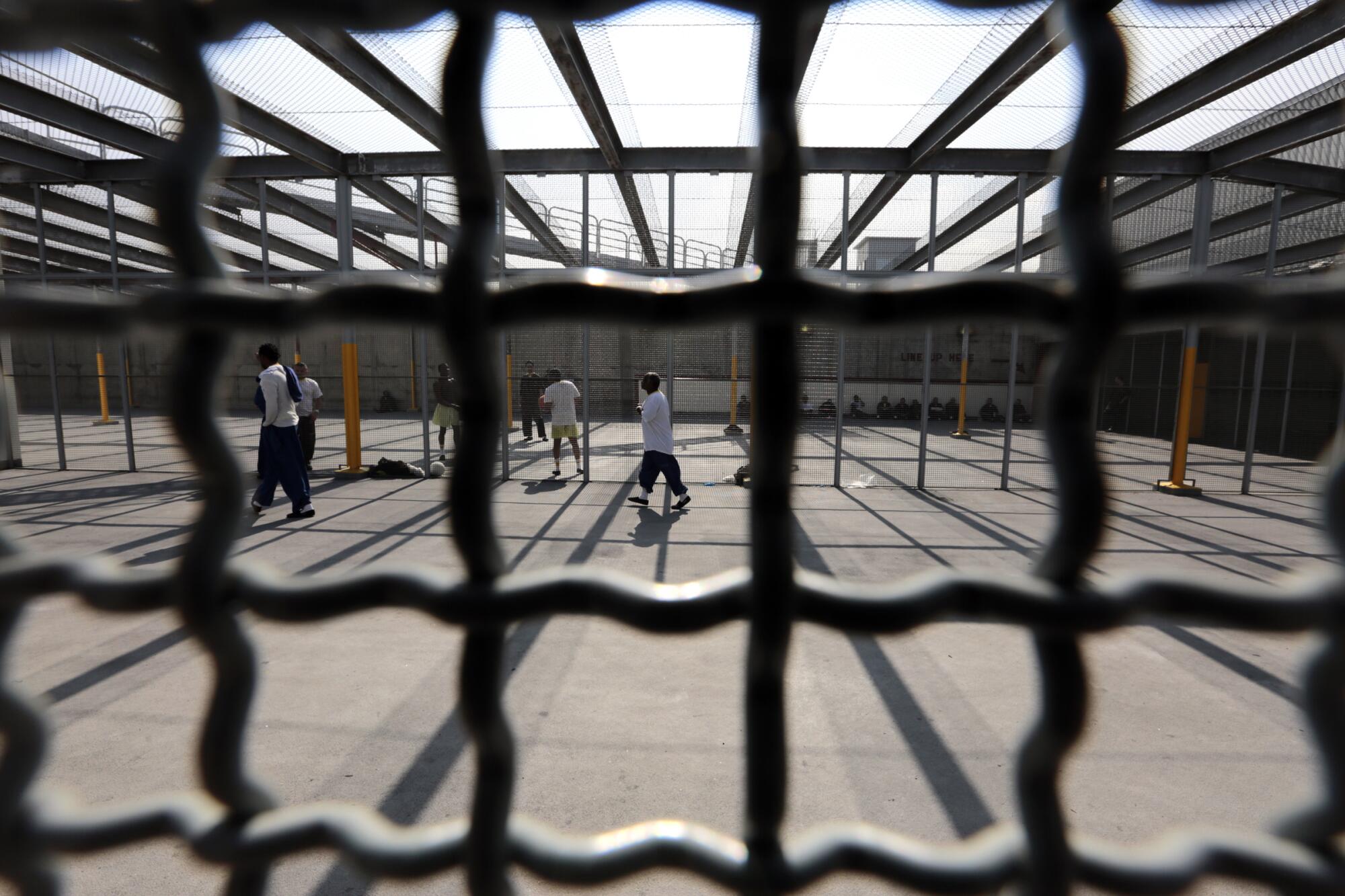 People in a yard are seen behind bars.