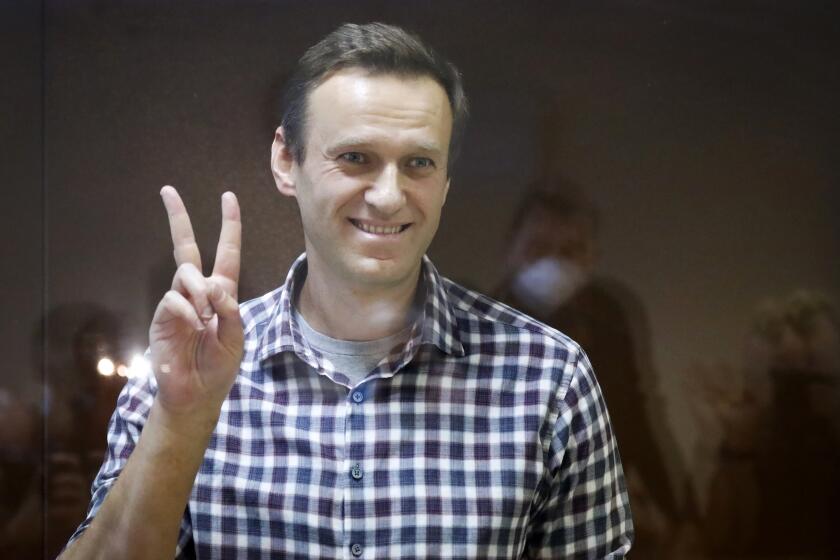 FILE - In this Saturday, Feb. 20, 2021 file photo, Russian opposition leader Alexei Navalny gestures as he stands in a cage in the Babuskinsky District Court in Moscow, Russia. Navalny marked the anniversary of a poisoning attack against him on Friday, Aug. 20 by urging global leaders to step up fight against corruption and target tycoons close to Russian President Vladimir Putin. (AP Photo/Alexander Zemlianichenko, file)