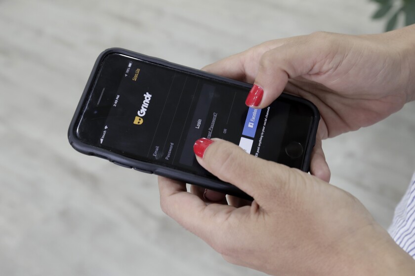 FILE - A woman looks at the Grindr app on her mobile phone in Beirut, Lebanon, May 29, 2019. Norway’s data privacy watchdog fined gay dating app Grindr $7.16 million for sending sensitive personal data to hundreds of potential advertising partners without users’ consent. The Norwegian Data Protection Authority said Wednesday, Dec. 15, 2021 that it imposed its highest fine to date because the California-based company didn’t comply with the European Union’s strict privacy rules. (AP Photo/Hassan Ammar, File)