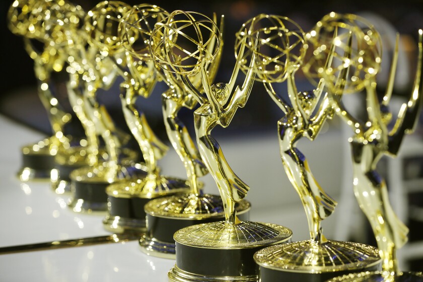 Close-up view of Emmy Award statues lined up in a row. 
