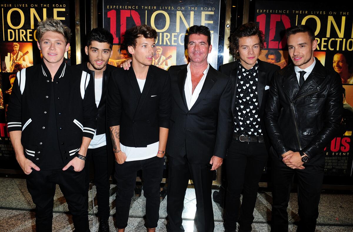 Simon Cowell standing amid the members of One Direction