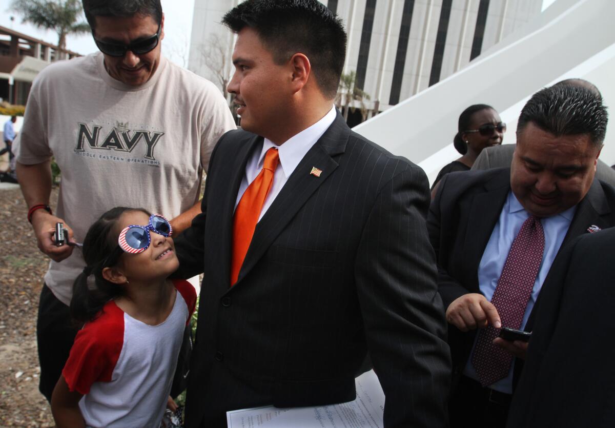 New Compton city councilman Isaac Galvan, center gets congratulations from Gary Valencia, left, and his daughter after Galvan was sworn in July 2. Galvan, 26, is the first Latino to serve as a city councilman in Compton.
