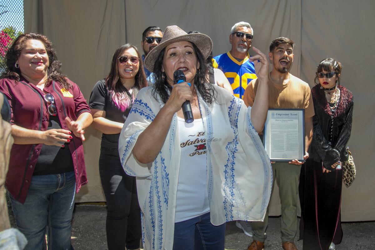 Surrounded by admirers, artist Marina Aguilera speaks at the unveiling of her El Salvador Park mural.
