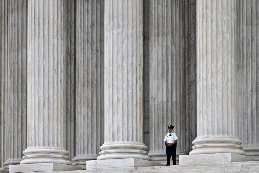 A police officer is dwarfed amid the marble columns of the Supreme Court in Washington on Oct. 7.