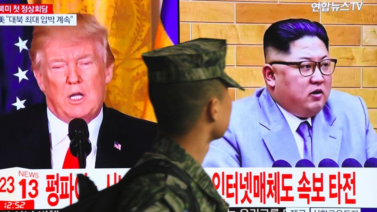 A South Korean soldier walks past a television screen in a Seoul railway station showing pictures of President Trump and North Korean leader Kim Jong Un.