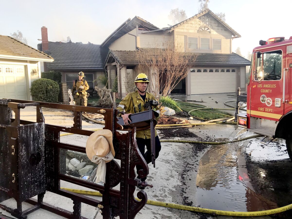 Firefighters carry furniture out of a home that was burned