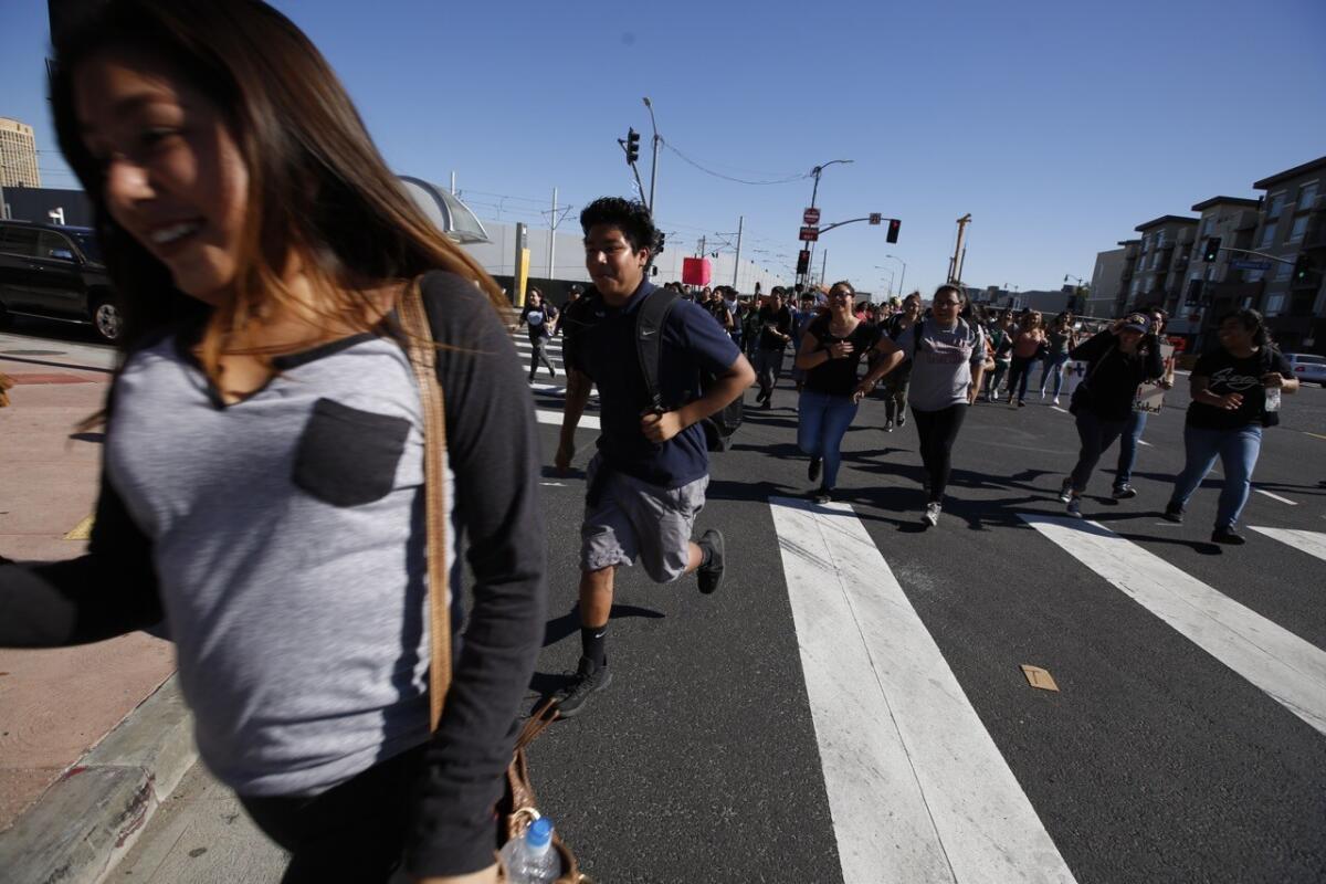 Students run across the intersection at 1st and Alameda streets during an anti-Trump walkout on Monday.