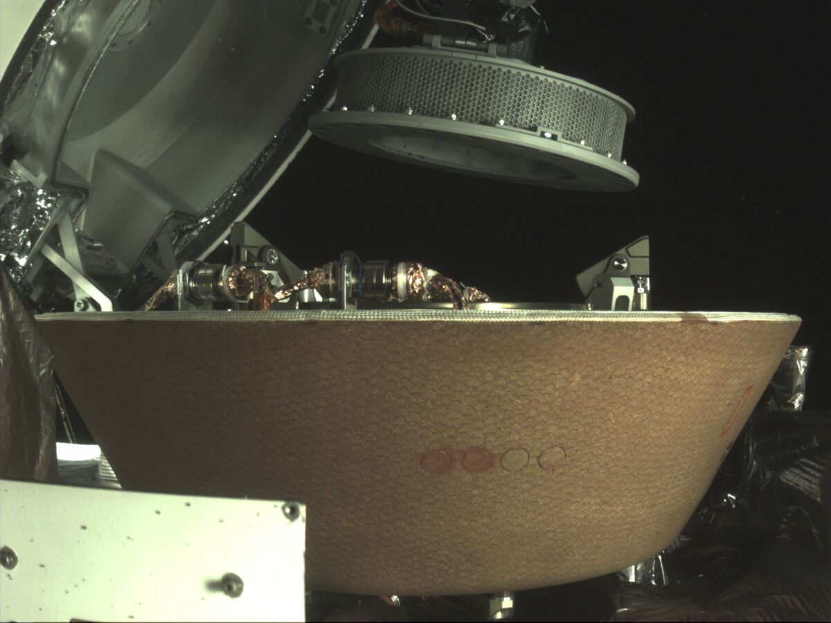 A sample container hovers over a capsule on NASA's Osiris-Rex spacecraft