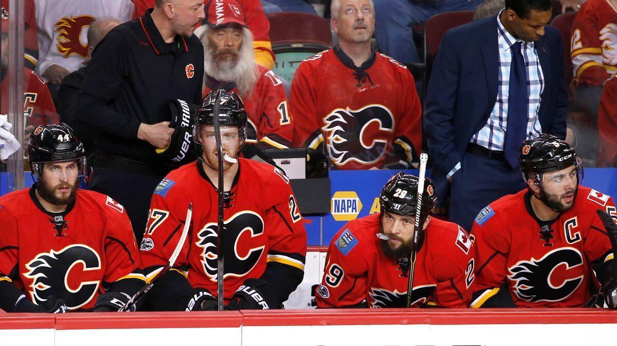 Calgary Flames players watch from the bench as the Ducks celebrate their overtime victory during Game 3 of a first-round Stanley Cup playoff series Monday.