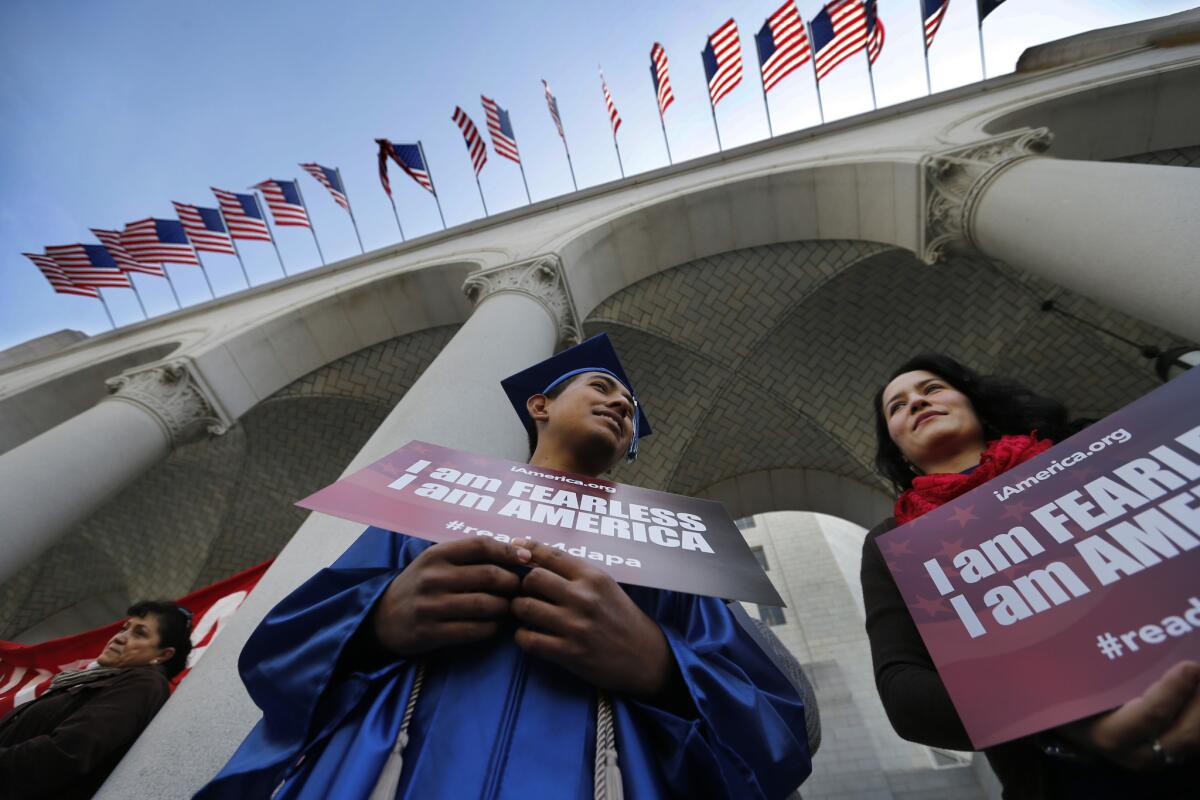 Jose Montes, 19, sporting his graduation cap and gown from Compton High School, and Paula Sarrad attend a pro-immigration rally at L.A. City Hall.