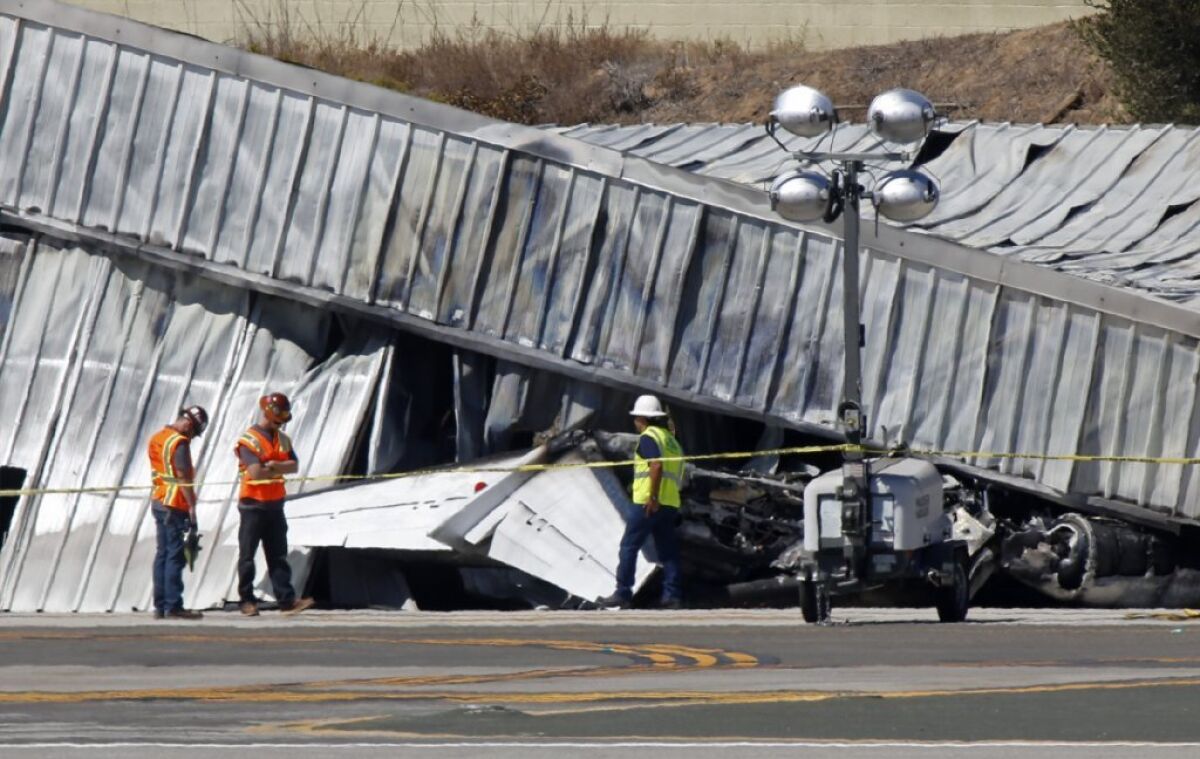 Investigators inspect the tail section of a twin-engine Cessna jet which ran off the runway and crashed into an aircraft hangar at Santa Monica Airport on Sept. 29.