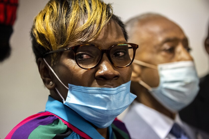 Tears streak down the cheek of a woman wearing a blue mask.