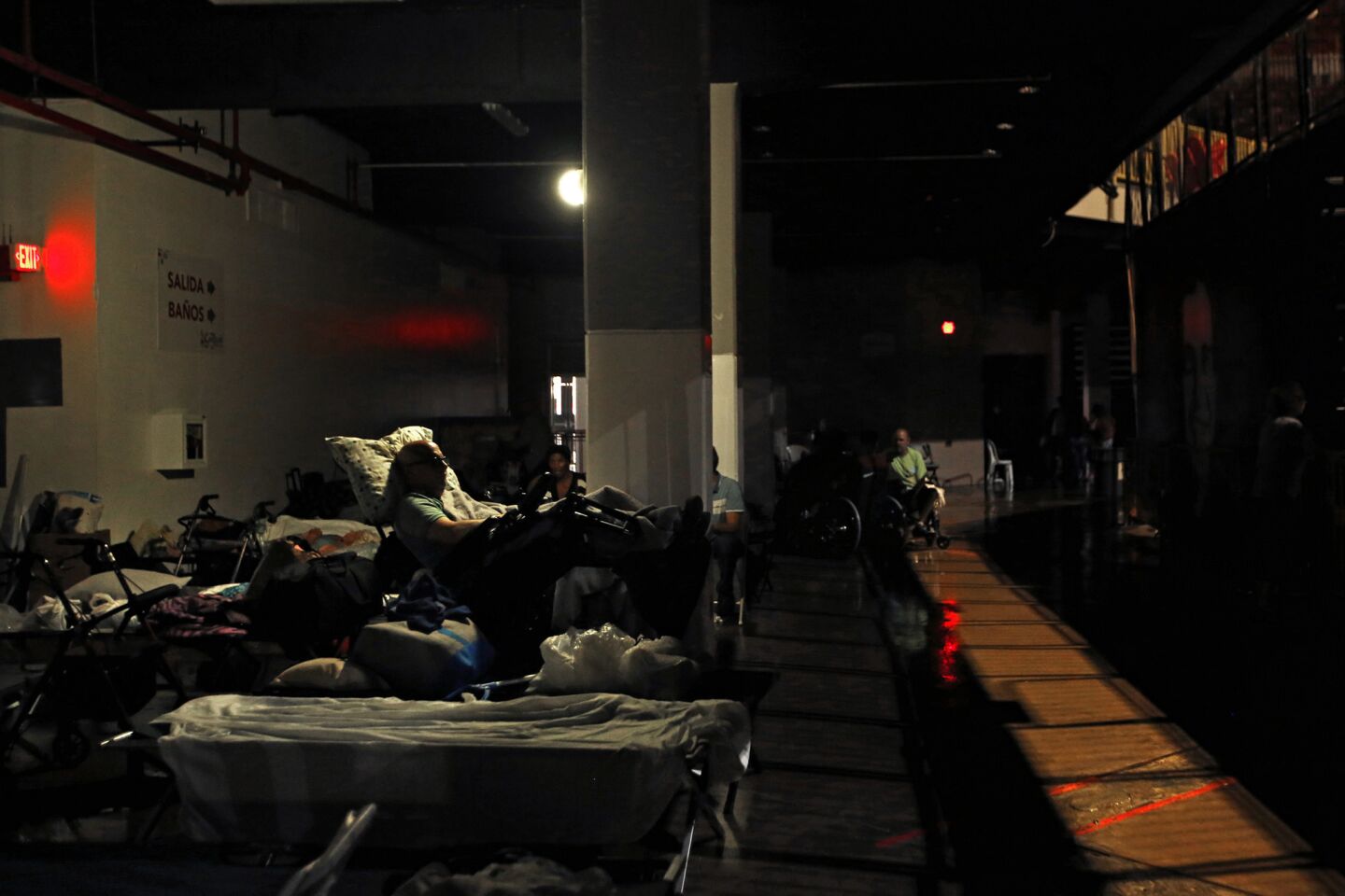 Evacuees rest in almost complete darkness on the ground floor of the Roberto Clemente Coliseum, a major shelter in San Juan.