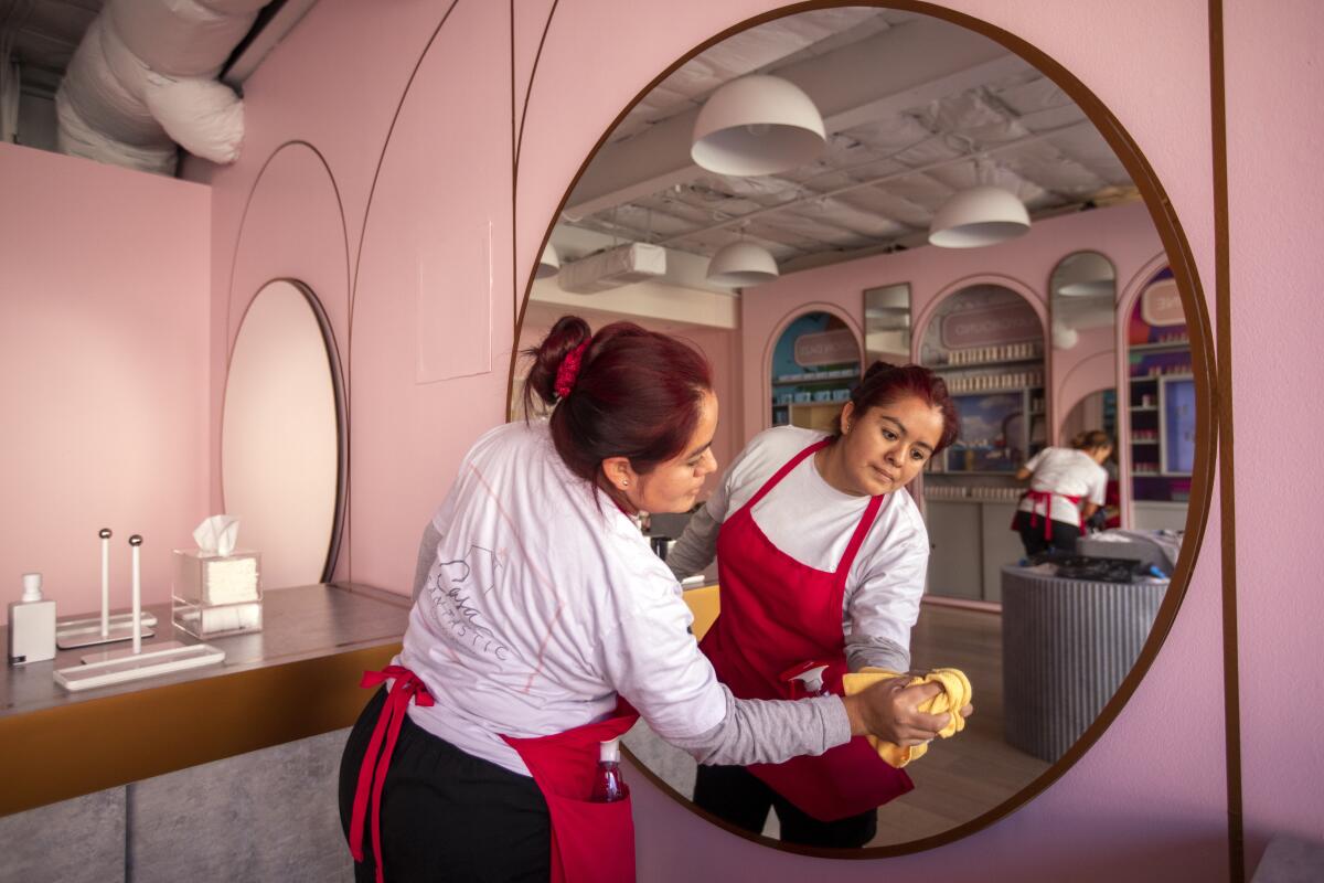 Erika Mijangos cleans a mirror at a commercial business 