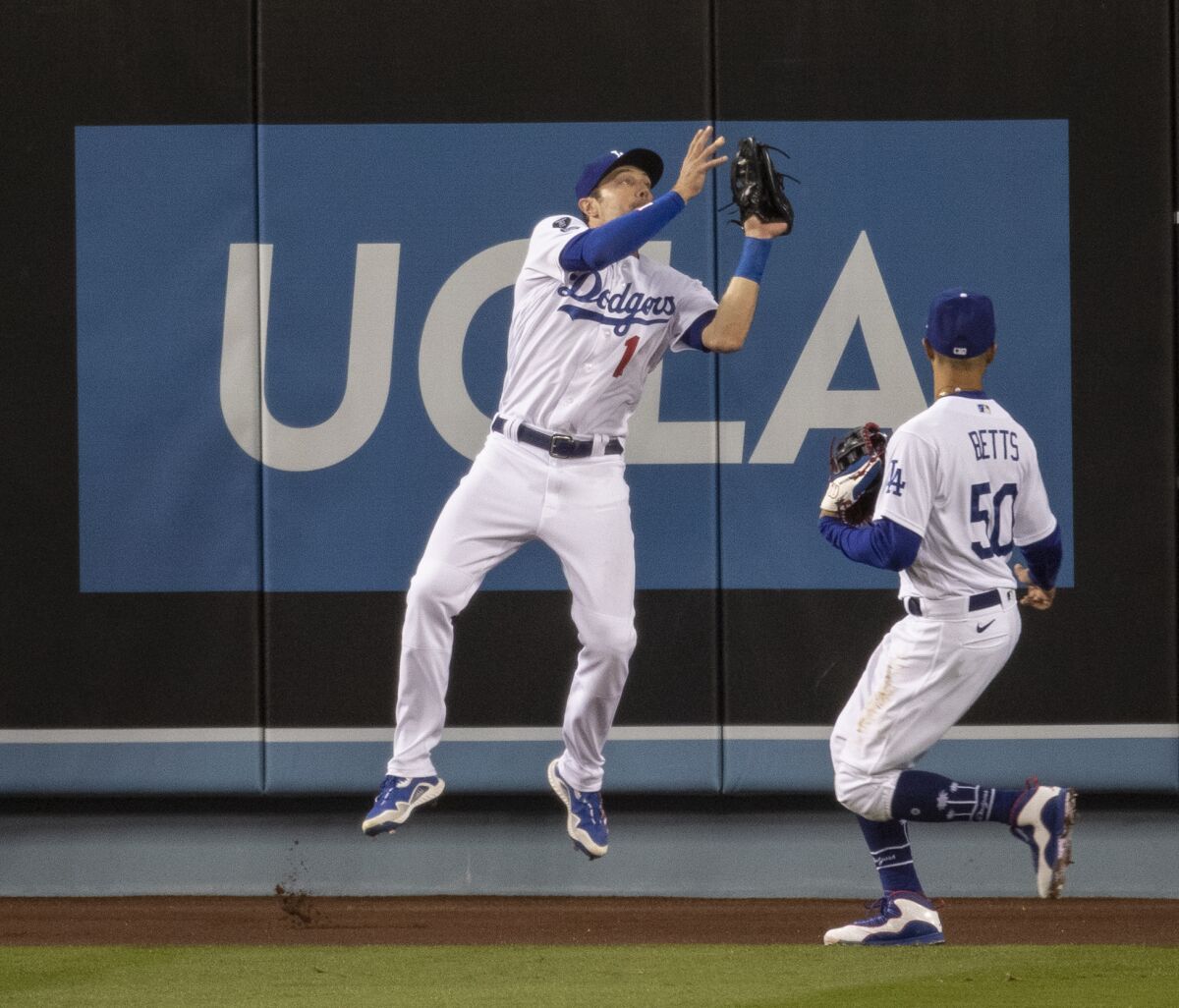 Dodgers left fielder AJ Pollock, left, makes a leaping catch at the warning track in front of teammate Mookie Betts.