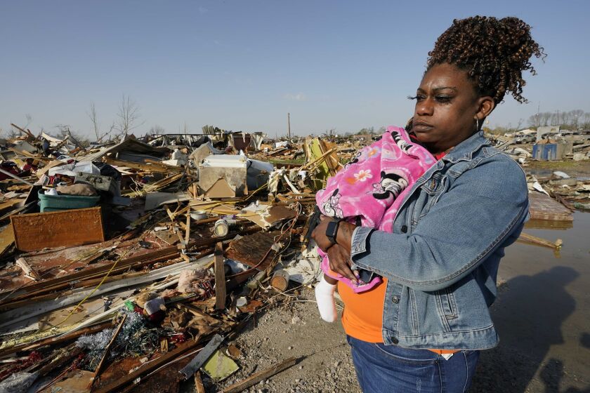 Wonder Bolden carga a su nieta de un año, Journey Bolden, junto a los restos de la casa rodante de su madre, demolida por un tornado, el sábado 25 de marzo de 2023, en Rolling Fork, Mississippi. (AP Foto/Rogelio V. Solis)