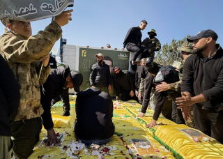 People put their hands on yellow-draped caskets strewn with flowers