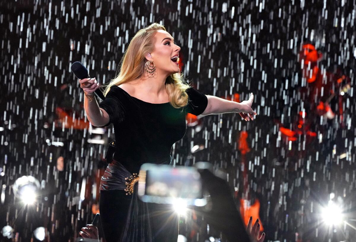 A female singer in a black dress performs onstage