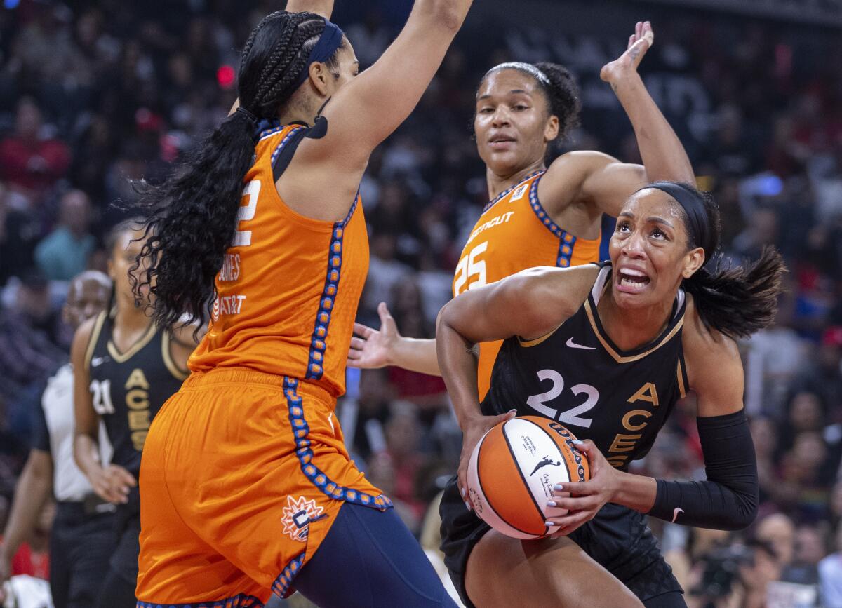 Las Vegas Aces forward A'ja Wilson (22) looks for a shot between Connecticut Sun center Brionna Jones (42) and forward Alyssa Thomas (25) during the first half in Game 1 of a WNBA basketball final playoff series Sunday, Sept. 11, 2022, in Las Vegas. (AP Photo/L.E. Baskow)